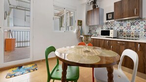 A kitchen with a tiled backsplash, wooden cabinets, a microwave, and a dining area with a round table and chairs. - Apartment 'Casacuéntame' with Private Terrace, Wi-Fi and Air Conditioning (Granada)