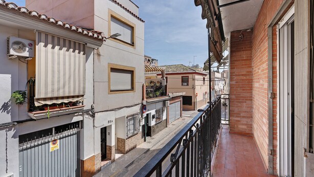 A narrow urban street with buildings, a balcony with a railing, and a gated entrance. - Apartment 'Casacuéntame' with Private Terrace, Wi-Fi and Air Conditioning (Granada)
