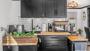 Una cocina moderna con armarios negros, encimera de madera, estufa integrada y un lavamanos.