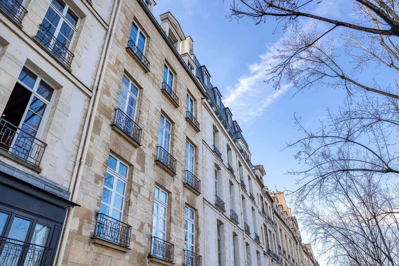 Un edificio de varios pisos con estilo arquitectónico clásico, que presenta ventanas y balcones uniformes.
