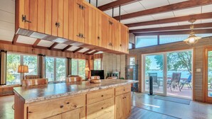 A spacious kitchen with wooden cabinetry, a large island, and a view of the outdoors.