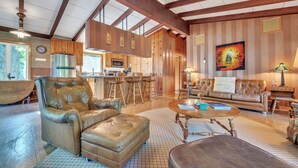 A spacious living area with a leather sofa, a coffee table, and a dining area with bar stools.
