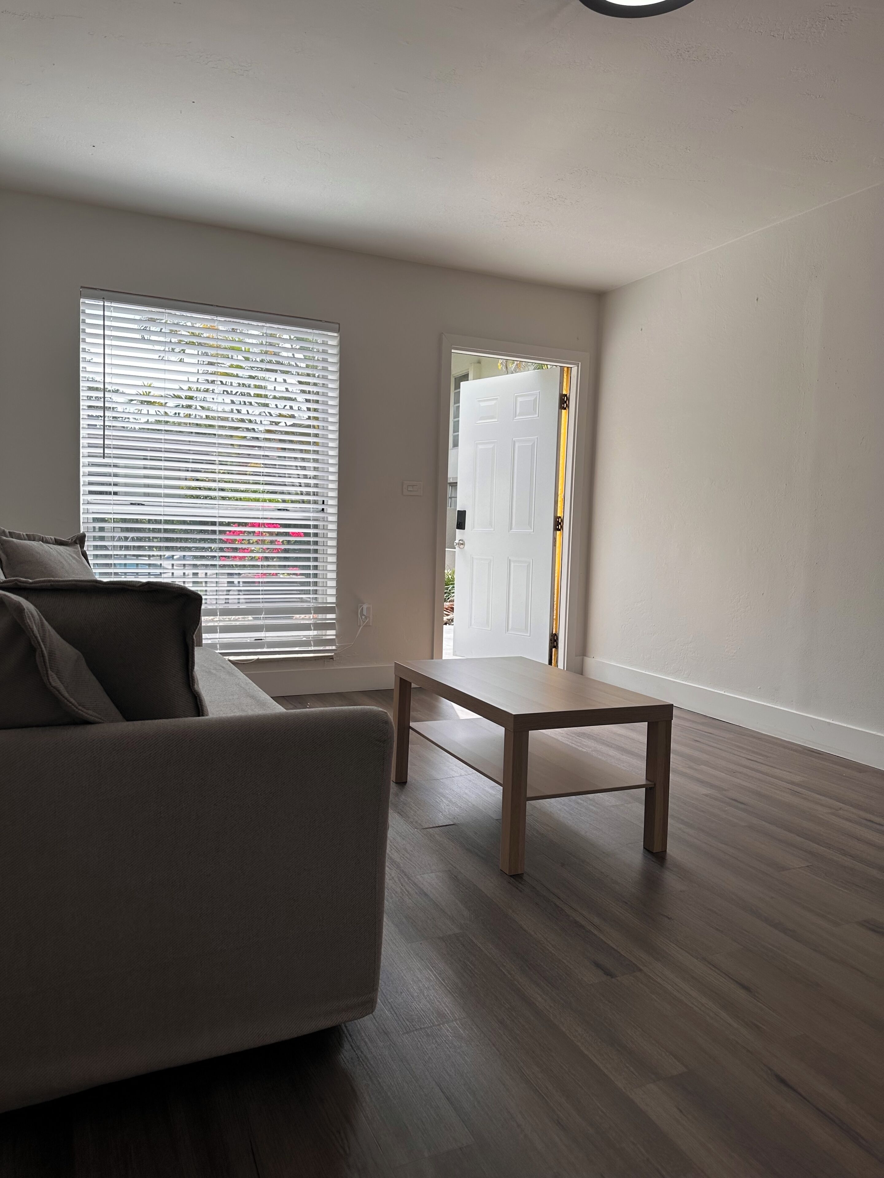 A living room with a sofa, a coffee table, and a door leading to another room.