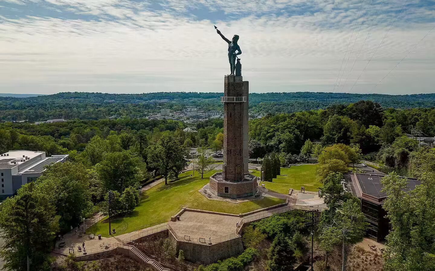 Un grand monument surmonté d’une statue, entouré d’un parc avec des allées et des arbres.