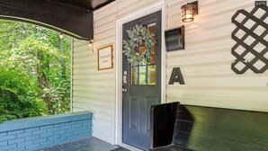 Una casa con una puerta oscura, un felpudo, un banco y un cartel que dice "HoneySuckle House".