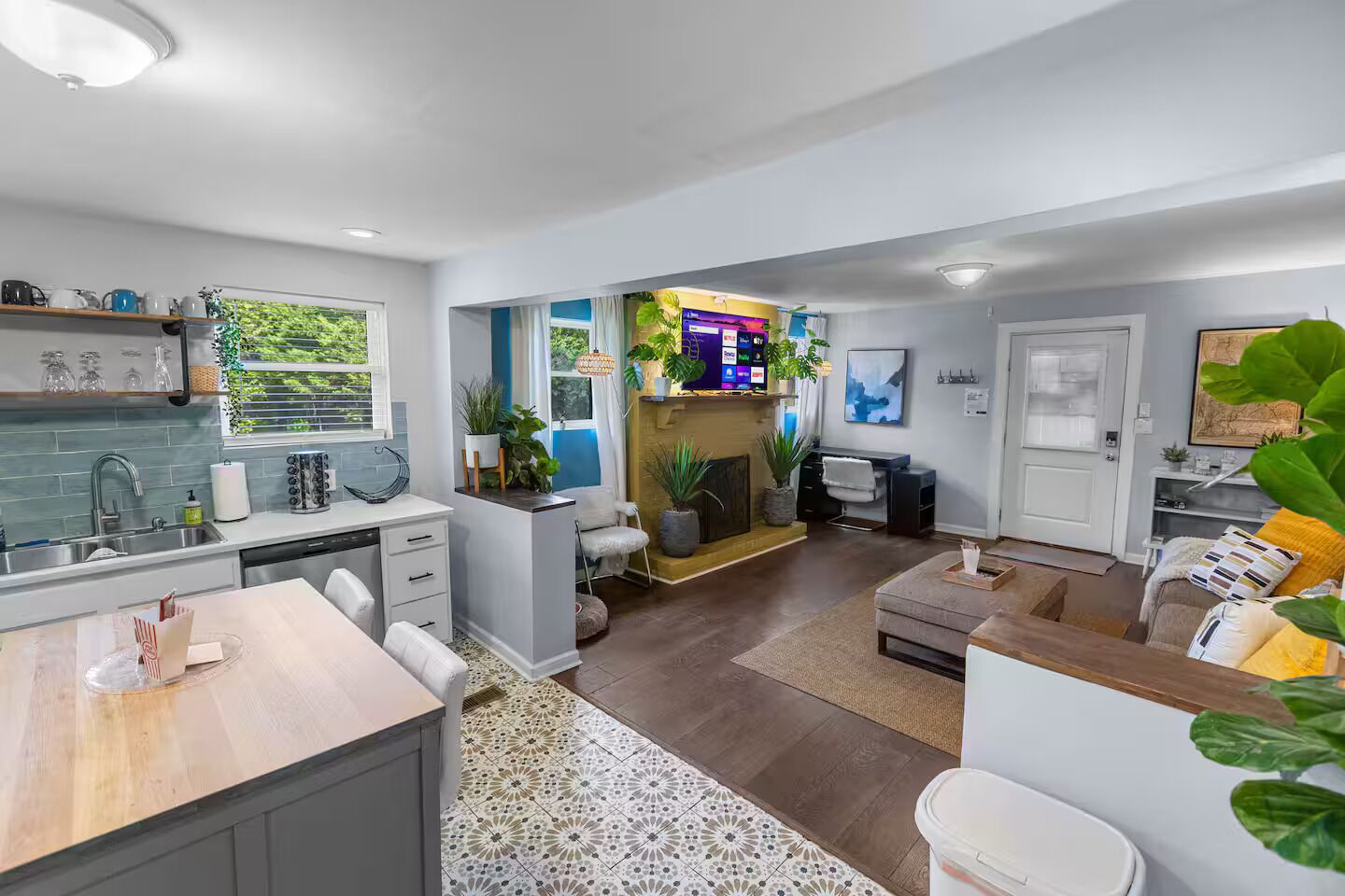 A modern kitchen with a dining area, a living room with a fireplace, and a TV.