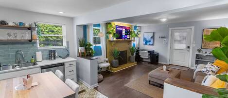 A modern kitchen with a dining area, a living room with a fireplace, and a TV.