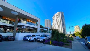 Un edificio moderno con un letrero que dice 'Slow & Life' y 'Pilates & Fitness', rodeado de coches estacionados y altos edificios residenciales.