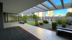 Un espacio exterior moderno con pared de vidrio, asientos y plantas.