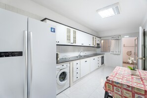 Una cocina moderna con lavadora, refrigerador y comedor con mesa.