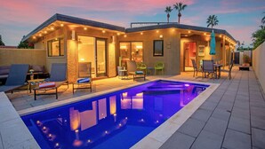 Une maison moderne dotée d’une piscine, d’un espace salon extérieur et d’un patio.