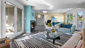 Un salon moderne avec une cheminée, un canapé, une table basse et un coin repas.