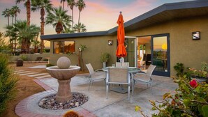 Une maison moderne dotée d’un patio, de mobilier d’extérieur et d’un élément décoratif en pierre.