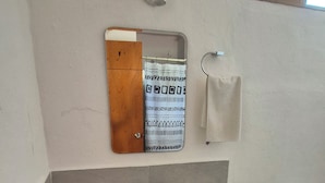Ein Badezimmer mit einem weißen Waschbecken, einem Spiegel, einem Handtuchhalter, einem blauen Hocker und einer Toilette.