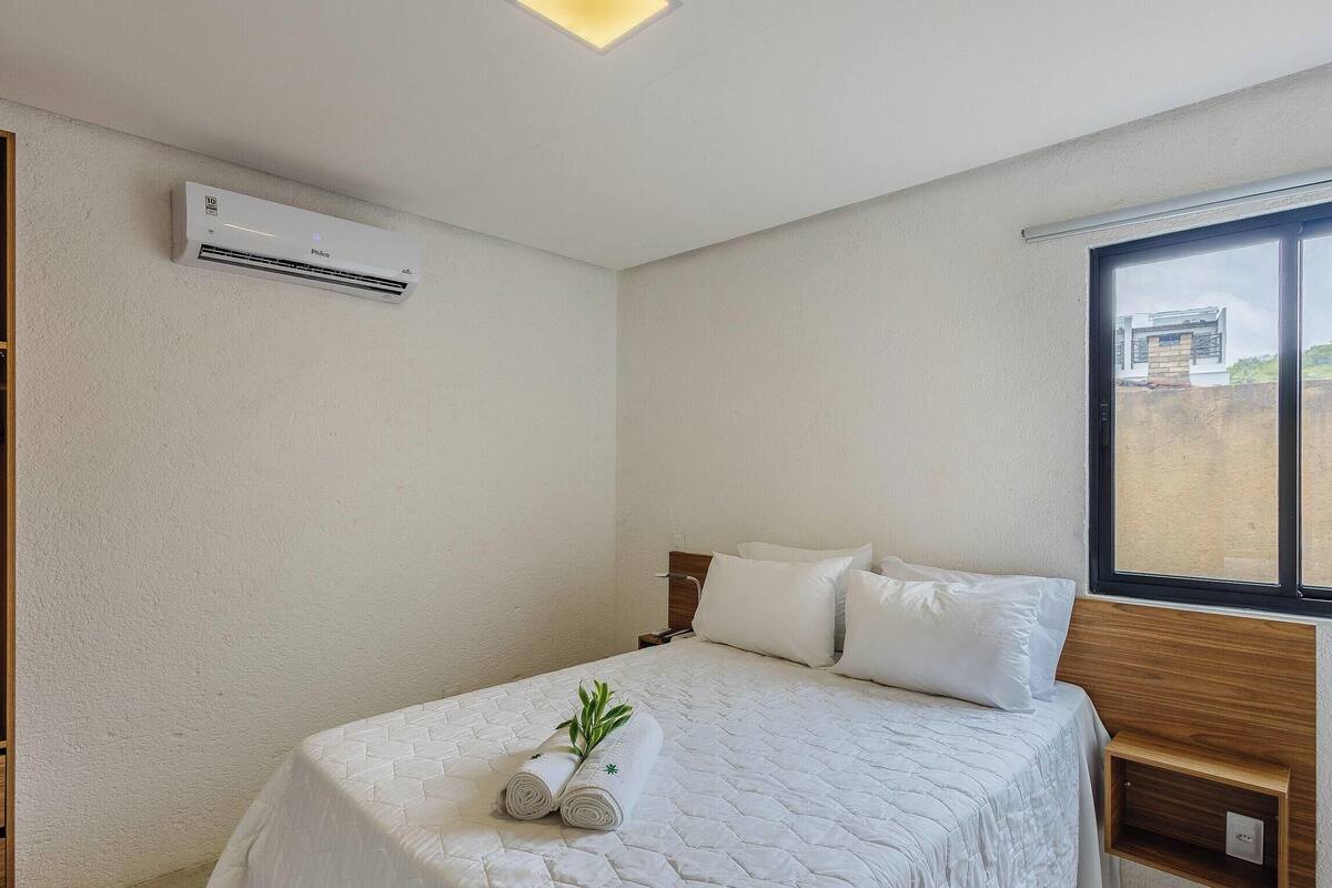 Una camera d'albergo con un letto, una finestra e un condizionatore.