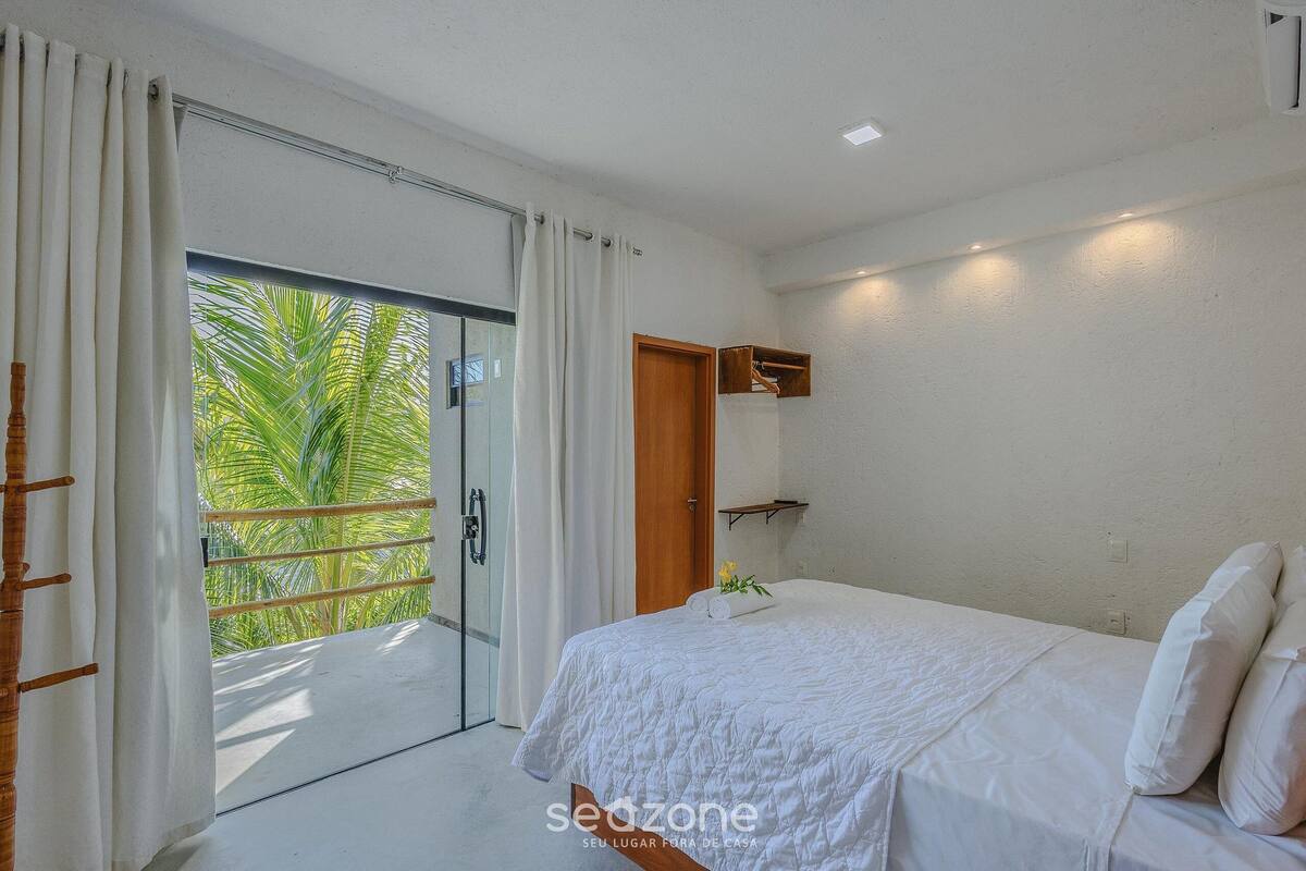 Una camera da letto con un letto, una porta, una finestra con tende e vista su palme.