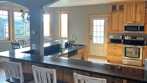 A spacious kitchen with a large island, wooden cabinets, and a view of the outdoors. - Ranch house in Arimo, Idaho with beautiful views, huge yard, and room to gather. (Arimo)