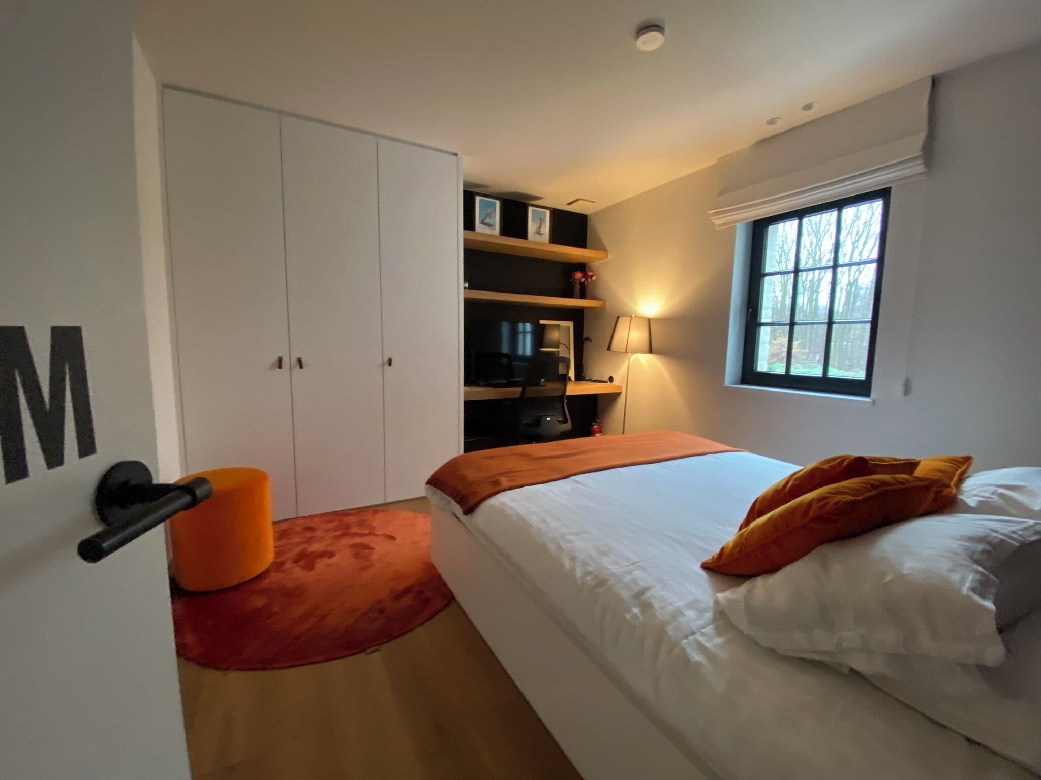 Une chambre à coucher avec un lit, un bureau, une chaise, une armoire et une fenêtre.