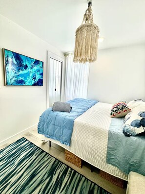 A bedroom with a bed, a hanging light fixture, a painting, and a window with curtains. - Luxurious Beachside retreat, 2 Bedrooms Entire rental unit in Queens, New York (Rockaway beach)