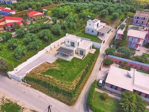 Vista aérea de uma área residencial com casas modernas, um amplo espaço aberto com painel solar e uma estrada.