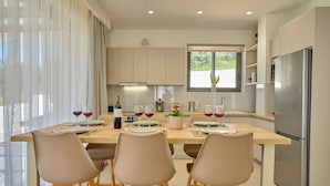 Una cocina moderna con una mesa de comedor preparada para cuatro personas, un refrigerador y un ventanal con vistas.