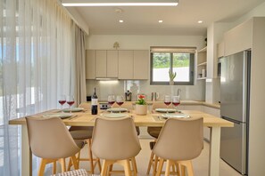 Uma cozinha moderna com uma mesa de jantar posta para quatro pessoas, uma geladeira e uma janela com vista.