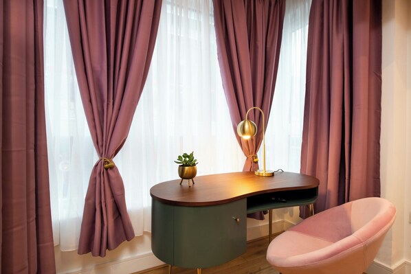 Une pièce avec un bureau, une chaise et des rideaux.