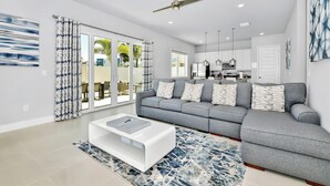 Ein modernes Wohnzimmer mit grauem Sofa, weißem Couchtisch und einem gemusterten Teppich.
