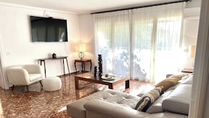 Un salon avec un canapé, une table basse, un téléviseur et une fenêtre avec des rideaux.