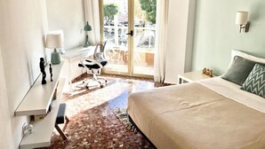 Une chambre d’hôtel avec un lit, un bureau, une chaise, une fenêtre avec des rideaux et une vue sur l’extérieur.