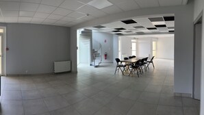 A spacious, modern interior with a large open area, a dining table with chairs, a staircase, and a view of the outdoors. - Group and stopover gîte in the heart of nature, on the Chemin de St Jacques GR65-GR7 (Riotord)