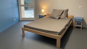 A bedroom with a bed, two bedside tables, a window, and a door. - Group and stopover gîte in the heart of nature, on the Chemin de St Jacques GR65-GR7 (Riotord)