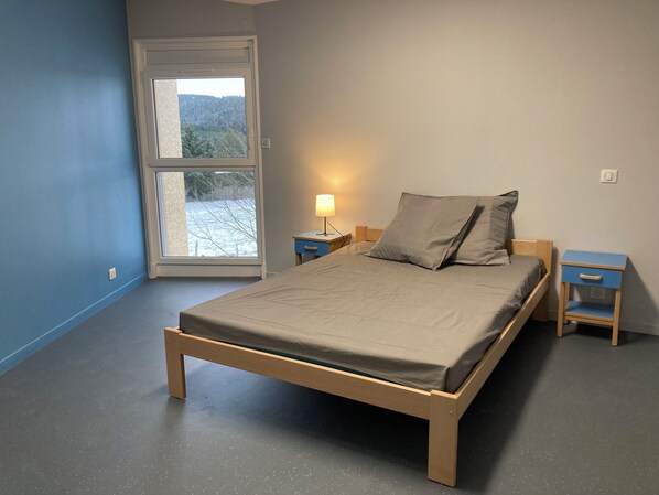 A bedroom with a bed, two bedside tables, a window, and a door.