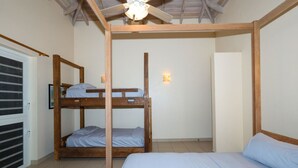 Una habitación con una cama litera, una cama individual, un ventilador de techo y una lámpara de pared.