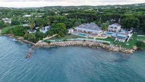 Vista aérea de una propiedad costera con una casa grande, piscina y costa rocosa.