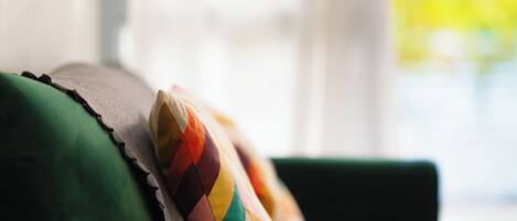 Un gros plan d’un coussin aux motifs multicolores, posé sur un canapé vert.