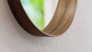 A curved mirror with a wooden frame mounted on a textured wall. - Sunset Lane (Holetown)
