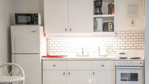 A compact kitchen with a microwave, coffee maker, toaster, and stove. - Sunset Lane (Holetown)
