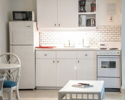 Una cocina compacta equipada con microondas, cafetera, tostadora y estufa.