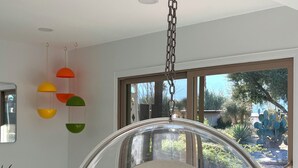 Een moderne kamer met een hangstoel, een eettafel met stoelen en uitzicht op het landschap.