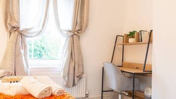 Et soveværelse med seng, skrivebord og radiator.