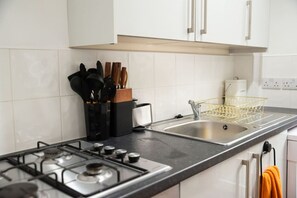 Une cuisine moderne équipée d’une cuisinière à gaz, de deux éviers et d’un égouttoir à vaisselle.