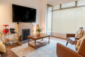 Un salon avec une cheminée, un téléviseur, un canapé et une table basse.