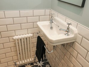 Un bagno con un lavandino bianco, un termosifone e un asciugamano nero appeso a un porta-asciugamani.