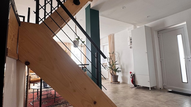 Una escalera con barandilla de madera y balaustres de metal negro, que conduce a un nivel inferior.