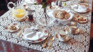 Una mesa dispuesta con vajilla de porcelana, cubiertos y un centro de mesa floral.