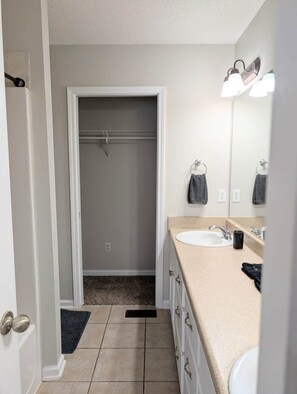 Un baño con un lavabo blanco, un espejo y un perchero para toallas.