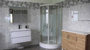 Une salle de bain avec une douche à parois de verre, un meuble-lavabo blanc avec un miroir et un placard en bois.