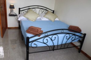 Un lit avec un matelas bleu, deux oreillers et deux serviettes pliées.