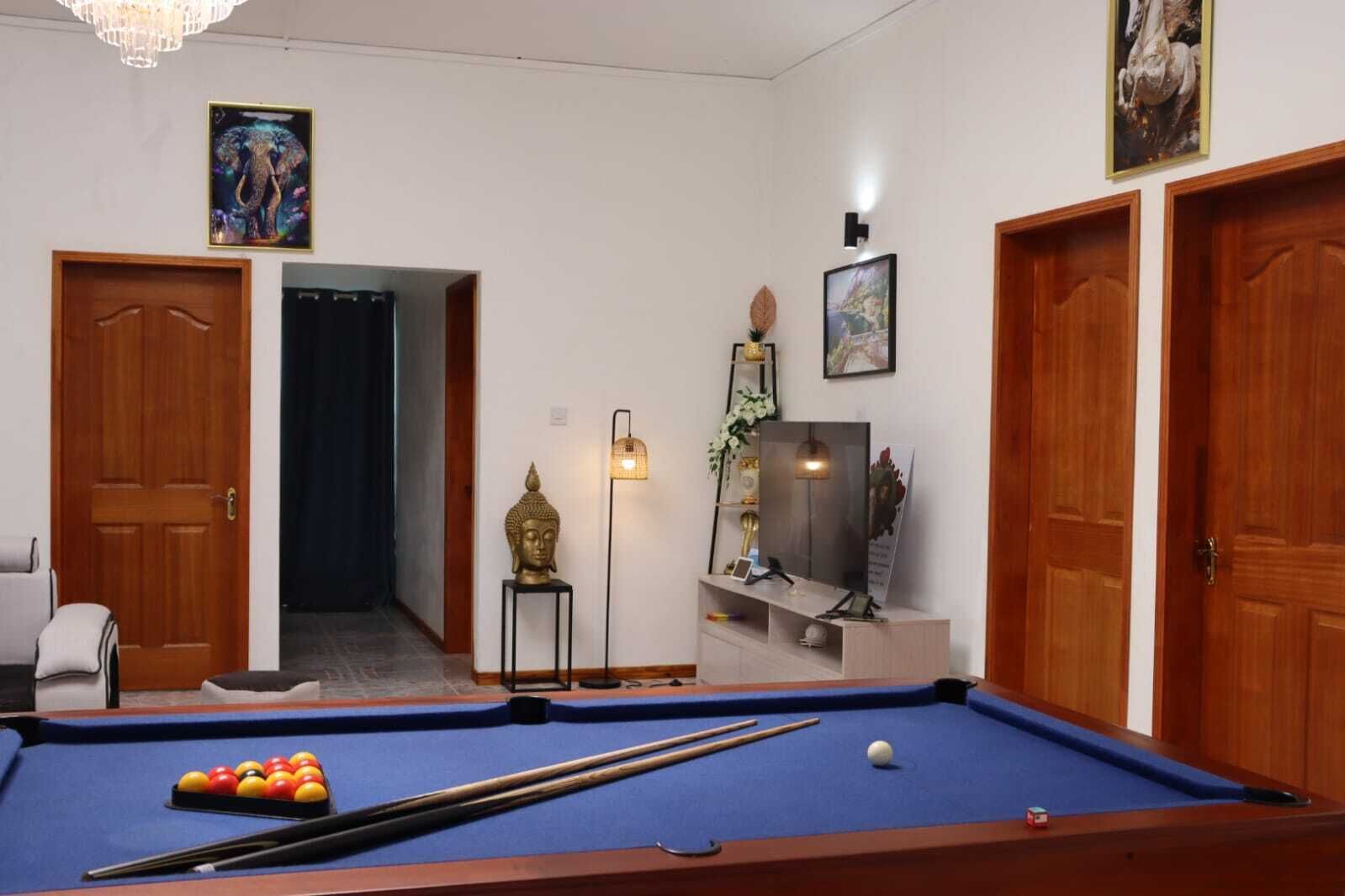 Une pièce avec une table de billard, une statue de Bouddha et un tableau encadré au mur.
